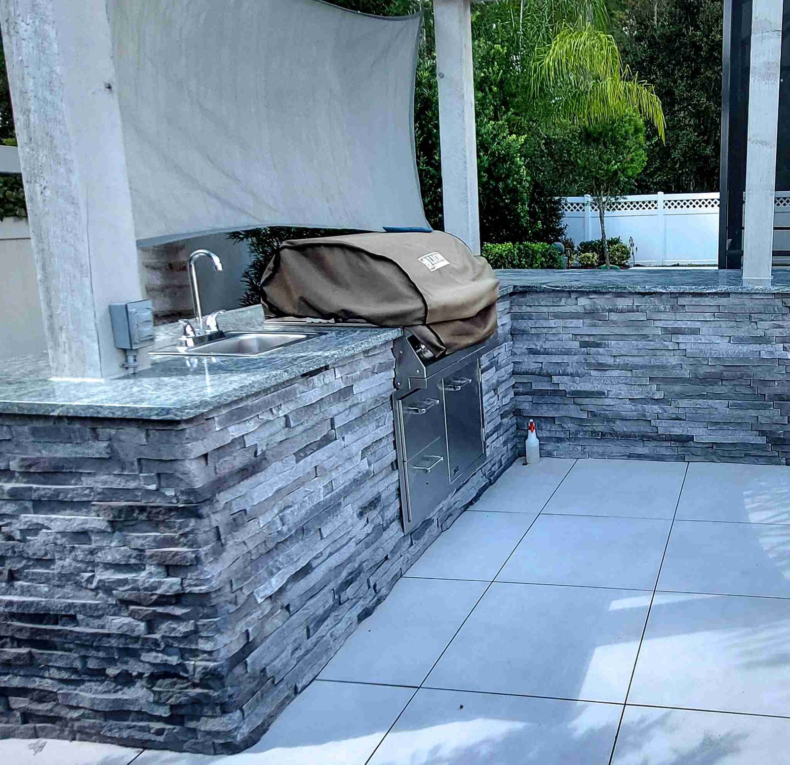 Outdoor kitchen with stacked stone veneer and grill